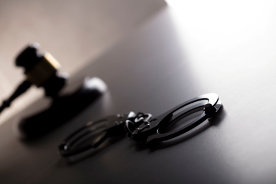 Gavel and handcuffs on a black desk