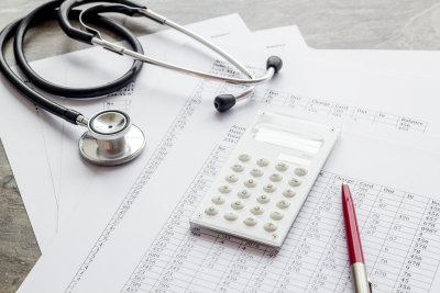 Calculator on sheet of paper next to pen and stethoscope