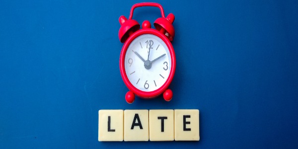 red alarm clock above letter blocks spelling 