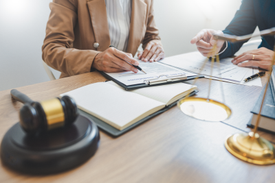 two professionals sitting at a lawyer's desk going over paperwork