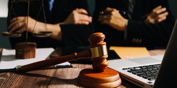 lawyers-discussing-contract-papers-with-brass-scale-on-desk-in-office