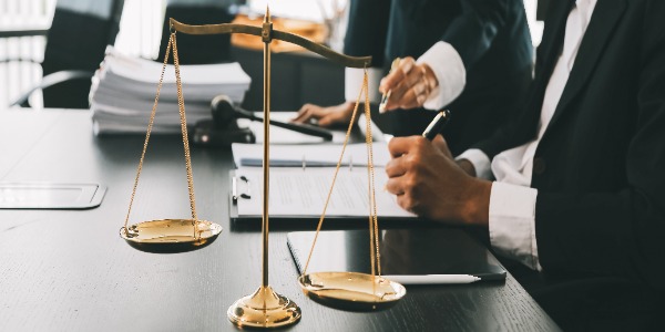 business-and-lawyers-discussing-contract-papers-with-brass-scale-on-desk-in-office