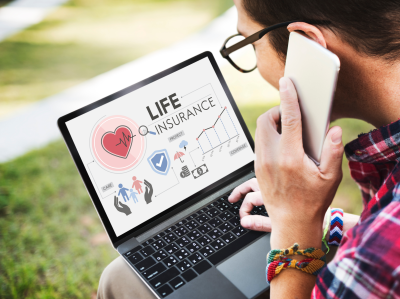 person researching life insurance on a laptop while talking on the phone