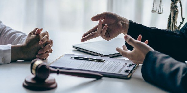 lawyer-working-with-client-discussing-contract-documents-with-brass-scales-on-law-in-courtroom