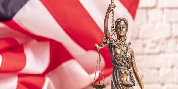 _the-statue-of-justice-themis-or-iustitia-the-blindfolded-goddess-of-justice-against-a-flag