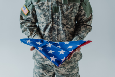 American soldier in uniform holding folded flag of United States